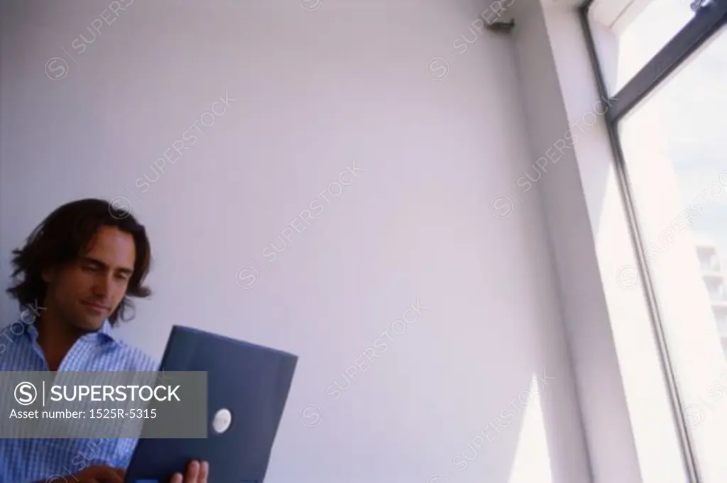 Low angle view of a young man working on a laptop