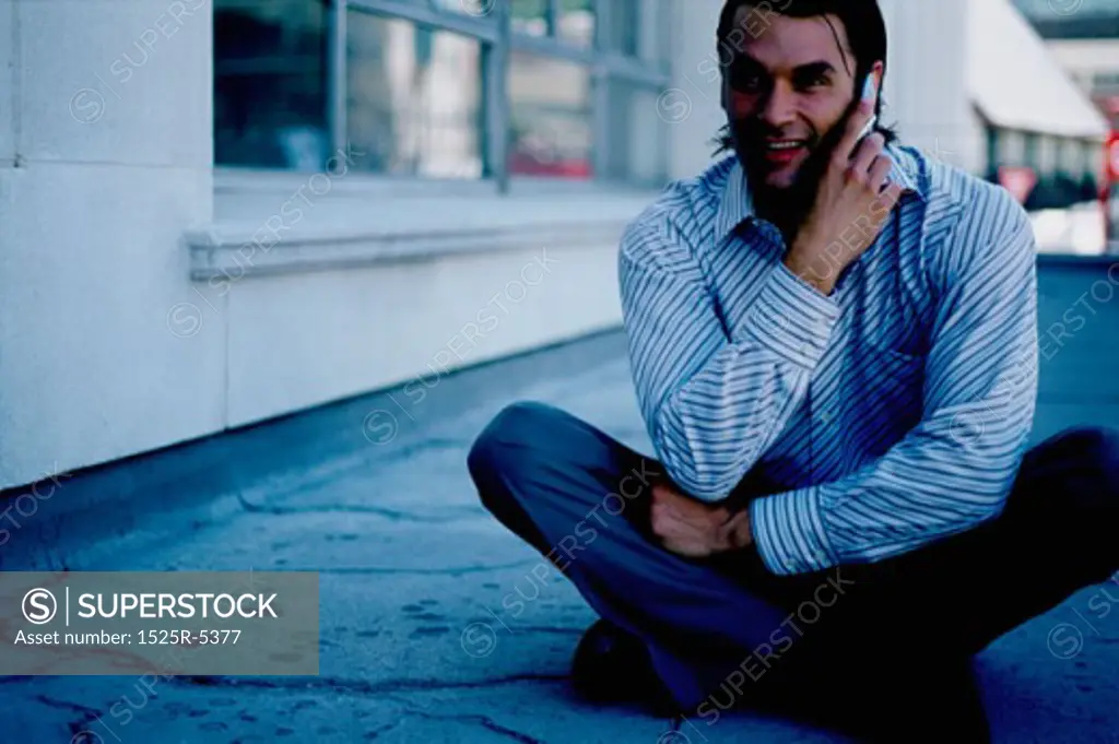 Close-up of a young man sitting on the floor and talking on a mobile phone