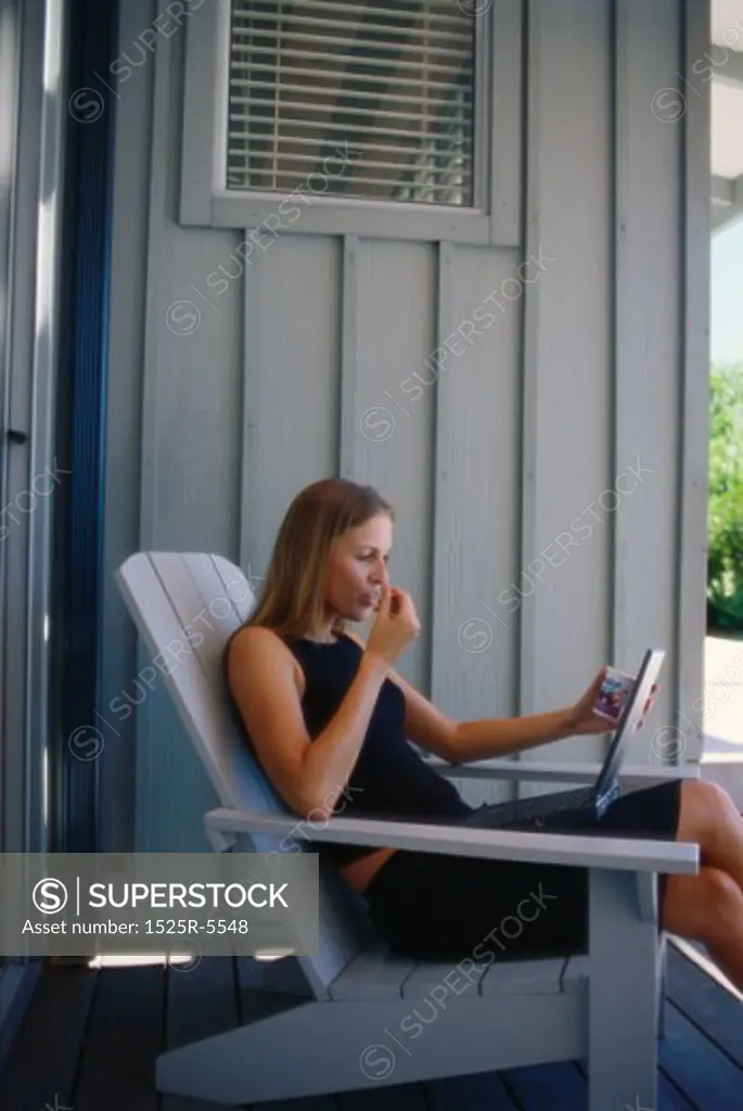 Side profile of a young woman sitting in a chair with a laptop