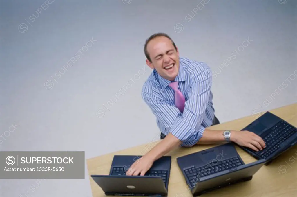 High angle view of a young man working on three laptops at the same time