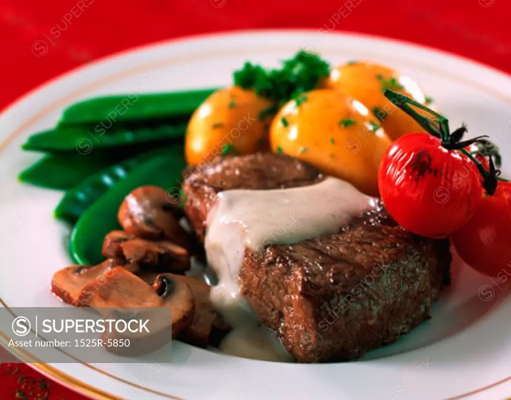 Close-up of prepared potatoes with cherry tomatoes and a steak on a plate