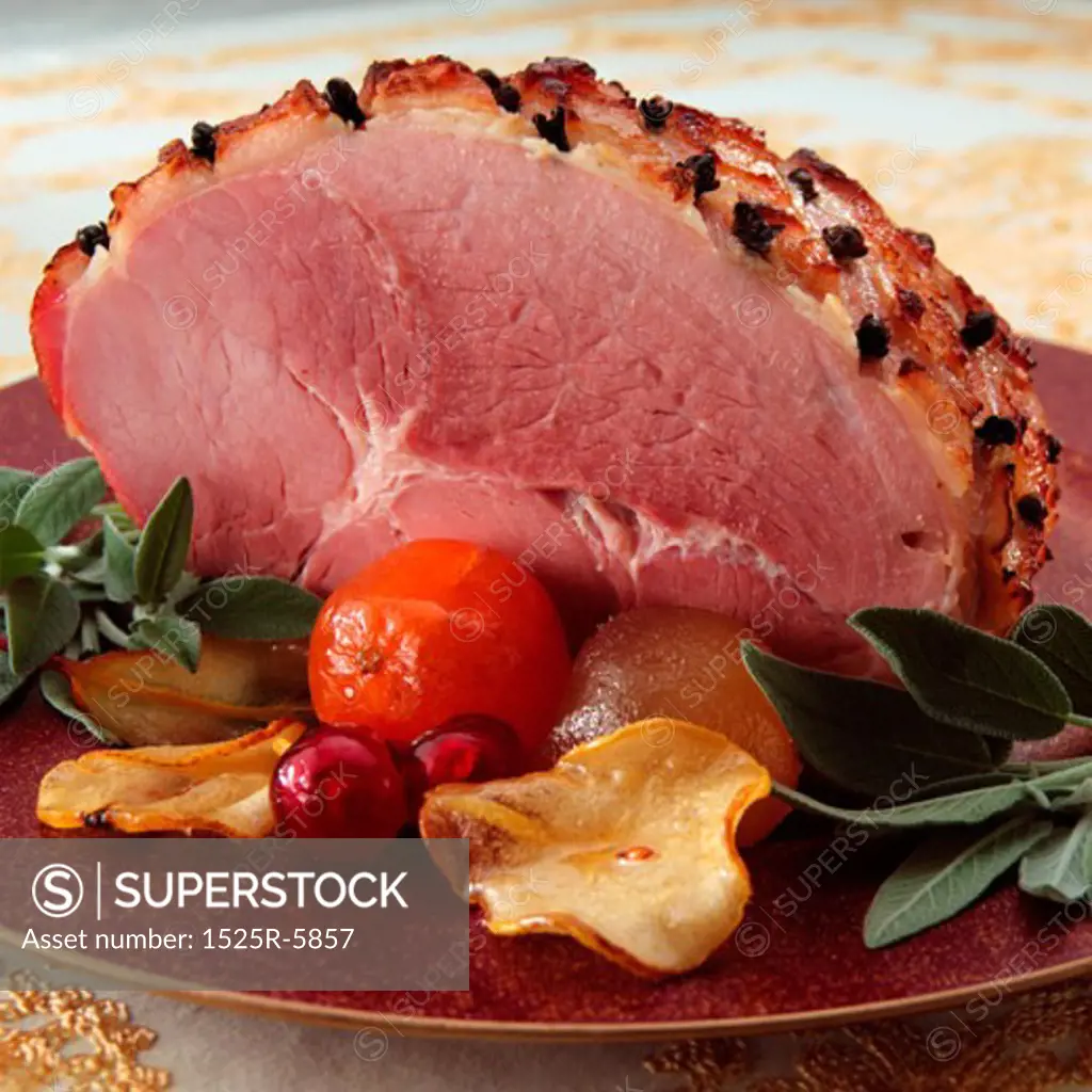 Close-up of ham with a tomato and plum on a plate