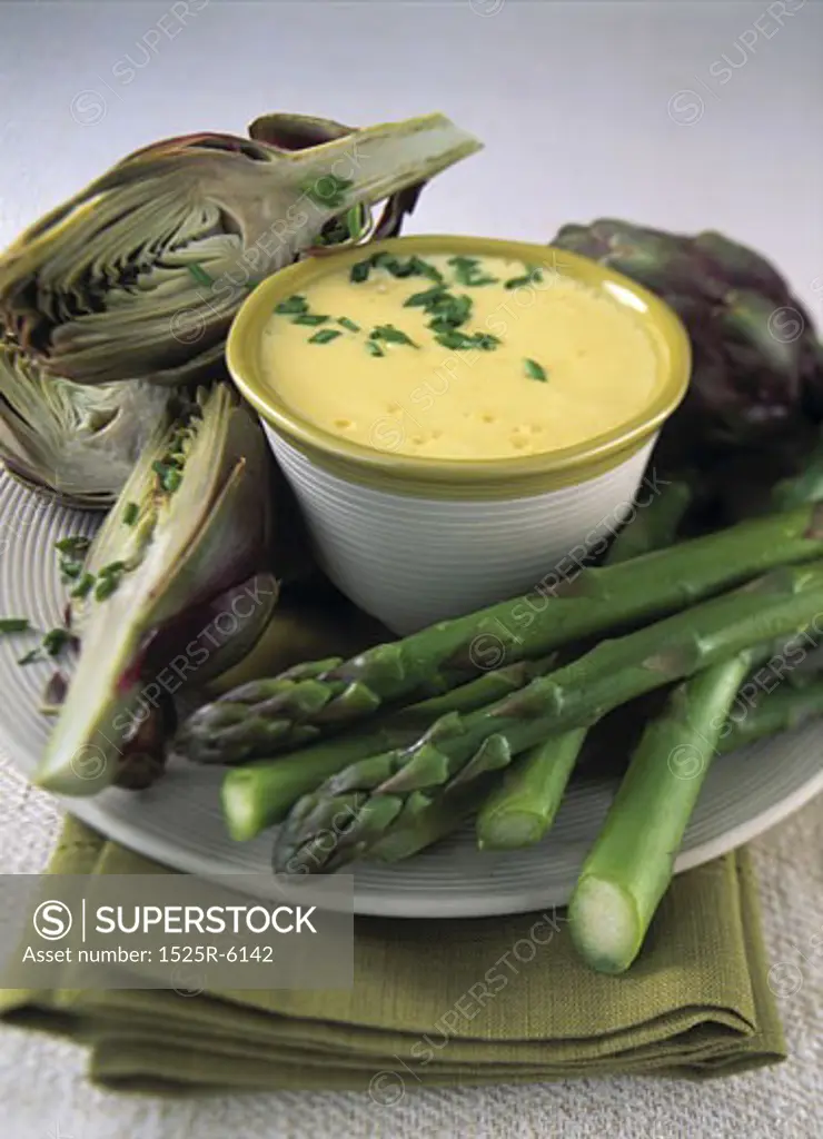 Close-up of a bowl of soup with artichoke and asparagus on a plate