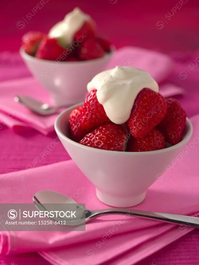 Close-up of cream on strawberries in bowls
