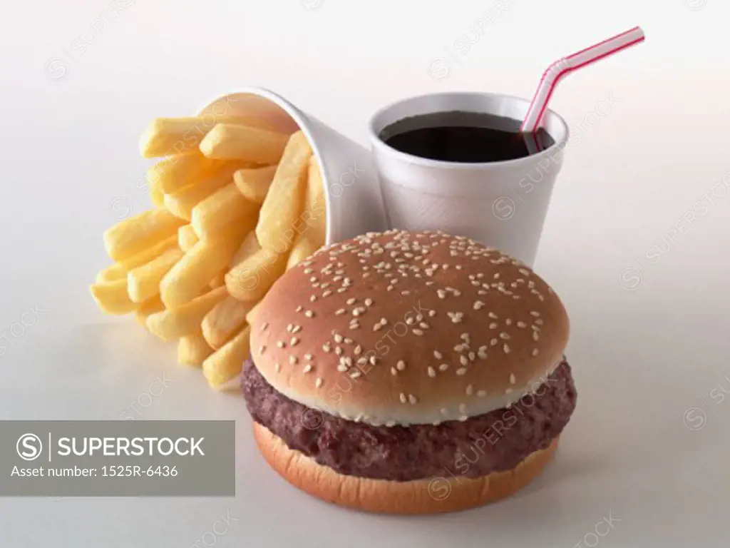 Close-up of a hamburger with a disposable cup of cold drink and French fries