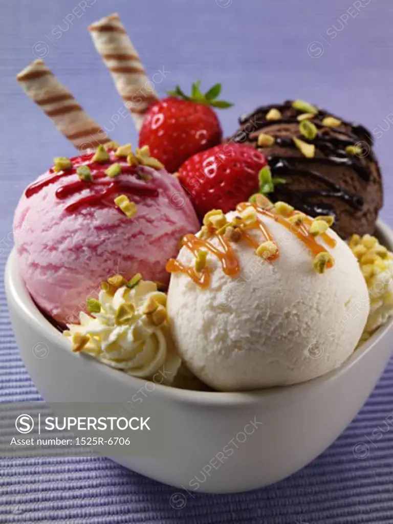 Close-up of three ice cream scoops with strawberries and nuts in a bowl