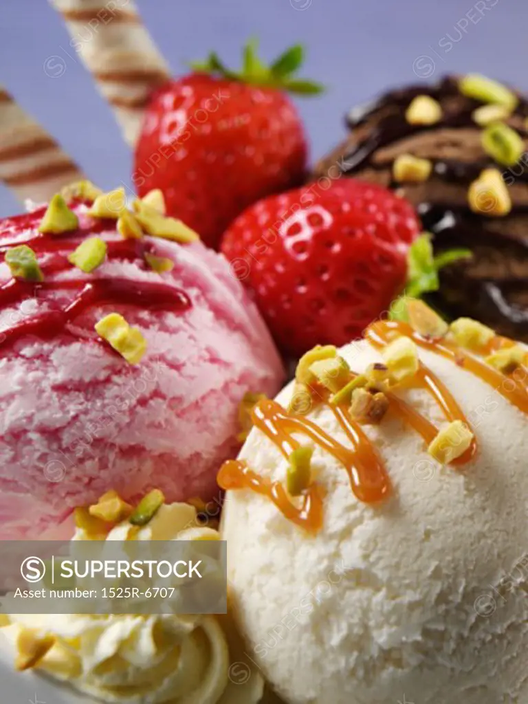 Close-up of three ice cream scoops with strawberries and nuts in a bowl