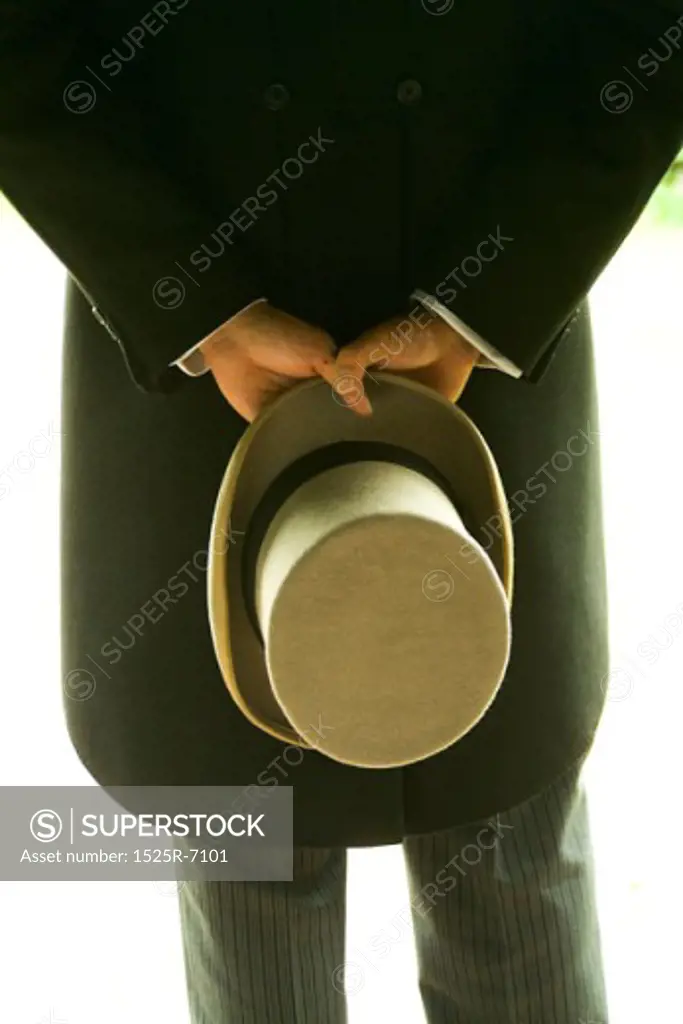 Rear view of a man holding a hat behind his back