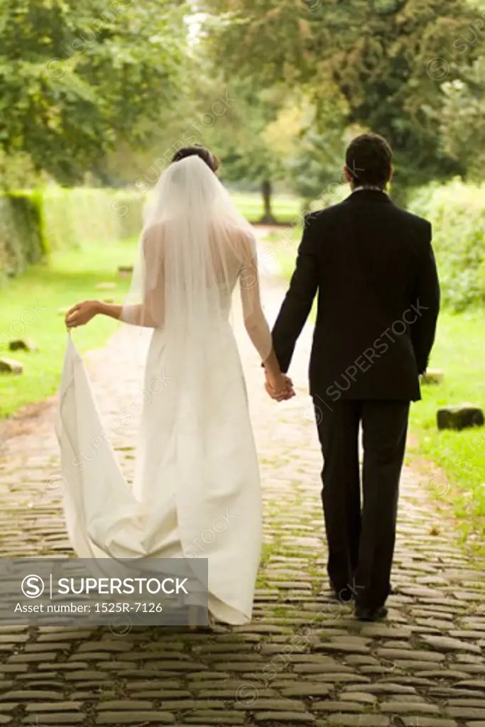 Rear view of a young bride and groom walking in a garden