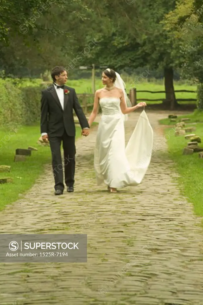 A newly married couple walking on a trail in a garden