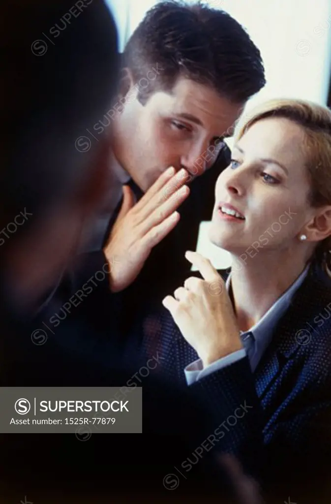 Businessman whispering into a businesswoman's ear