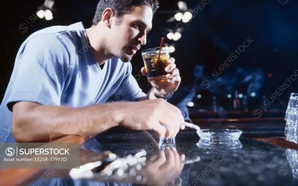 Young man smoking a cigarette and drinking alcohol