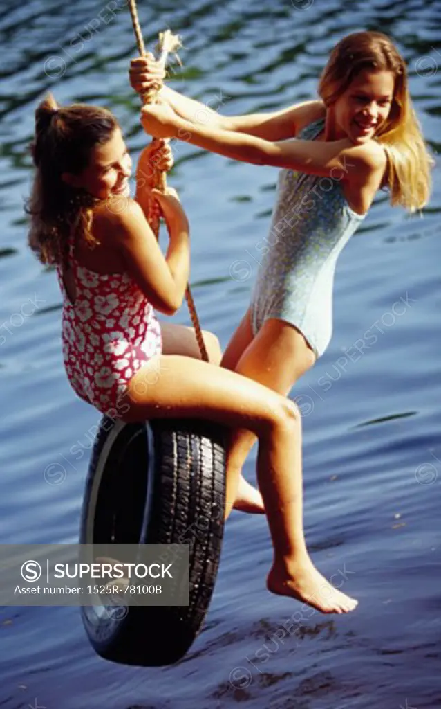High angle view of two girls swinging on a tire swing