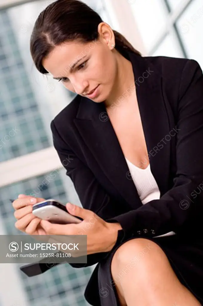 Close-up of a businesswoman operating a mobile phone with a digitized pen