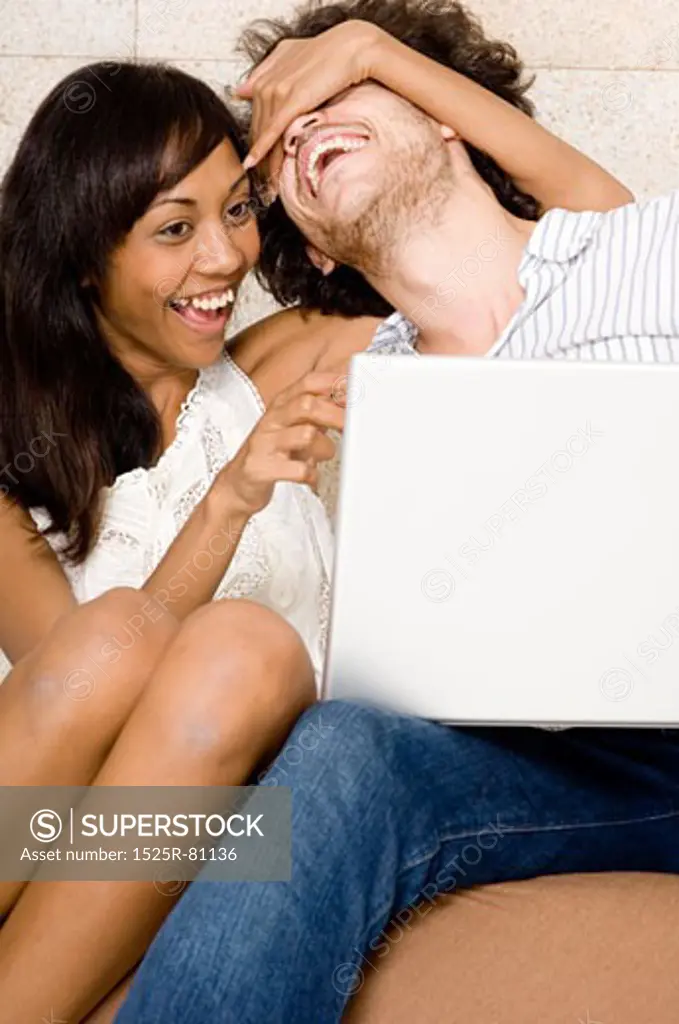 Close-up of a young couple sitting in front of a laptop and laughing