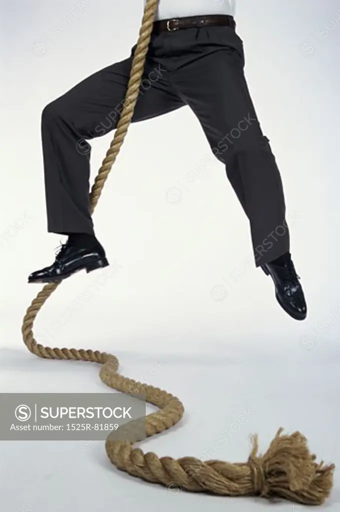 Low section view of a man climbing a rope