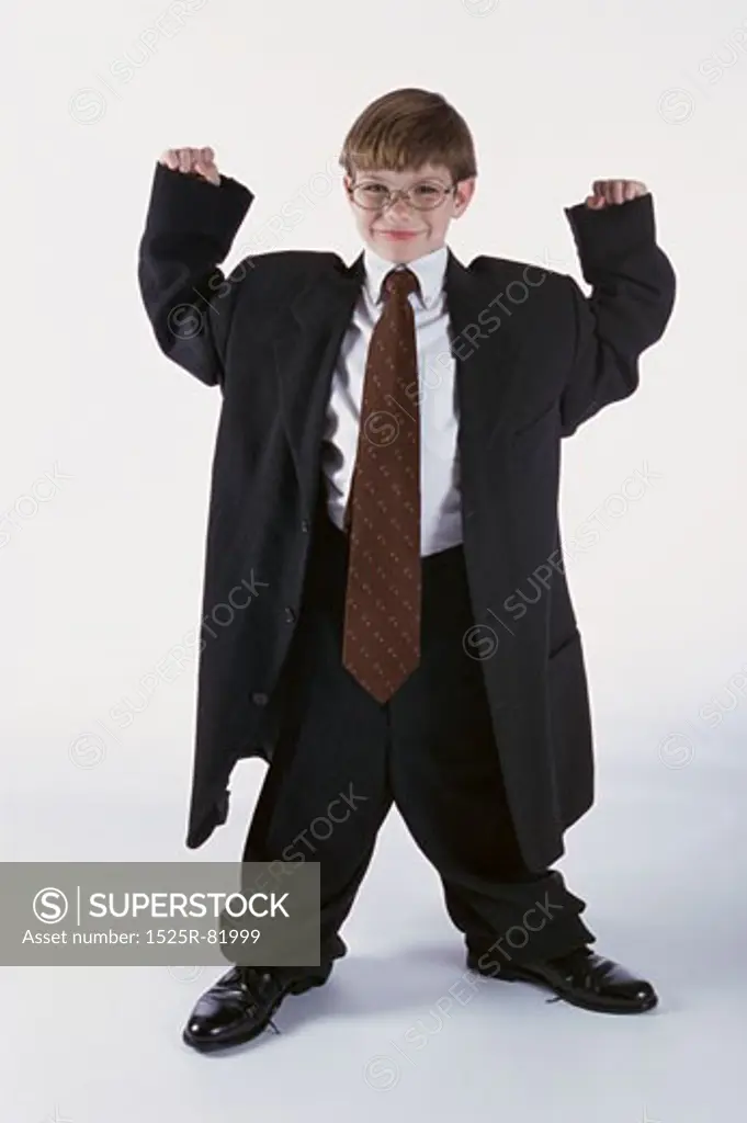 Portrait of a young boy dressed as a businessman with his arms raised