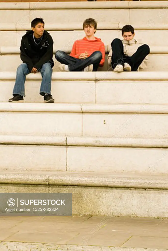 Three teenage boys sitting on steps