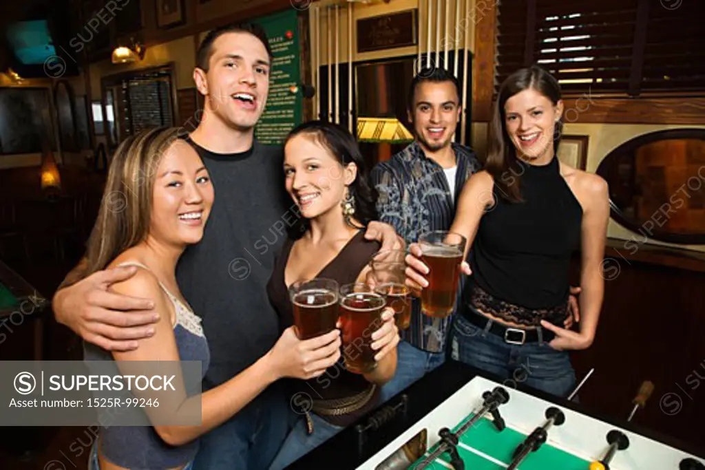Portrait of group of young friends hanging out in pub and drinking beer.