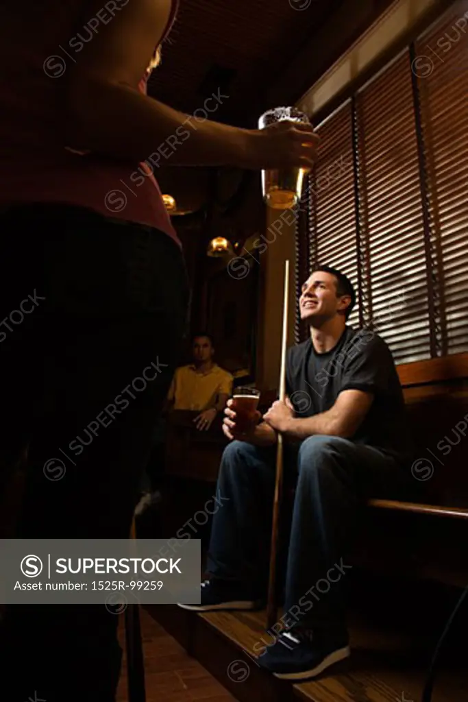 Young man holding billiards cue while hanging out at pub.
