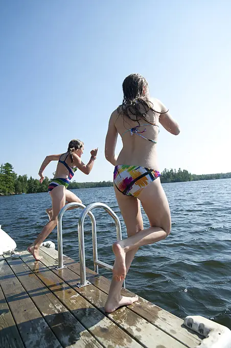 Girls jumping into the water at Lake of the Woods, Ontario