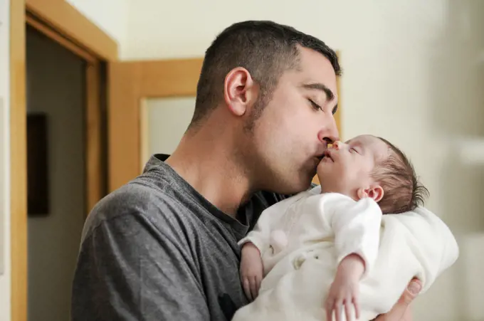 Father kissing his newborn baby girl. Close-up portrait