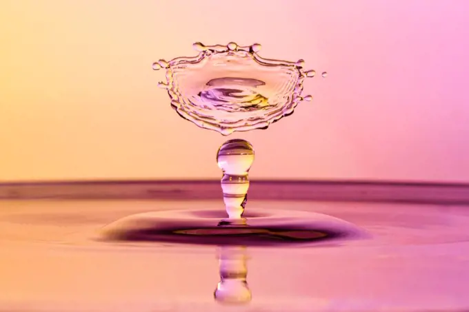 High speed water drop photograph with colliding drops in orange and purple colors. High speed water drop photograph with colliding drops