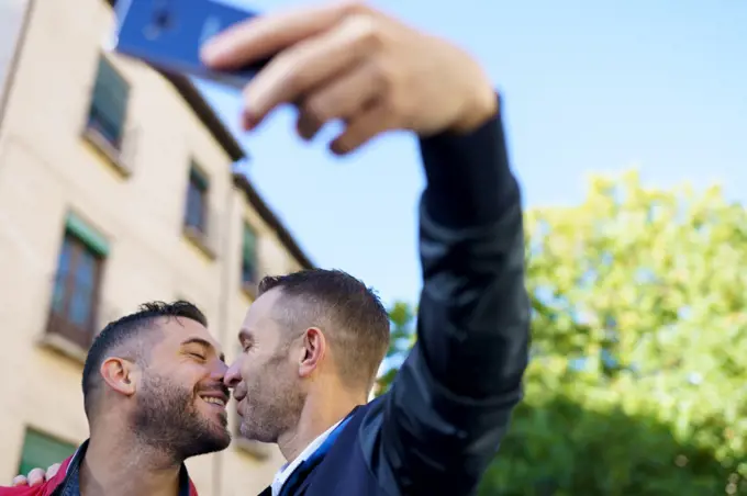Gay couple making a selfie with their smartphone. Homosexual relationship concept.. Gay couple making a selfie with their smartphone.