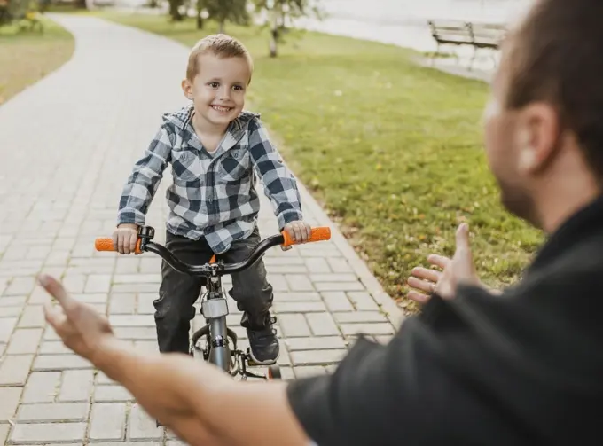 dad teaching his child how ride bicycle
