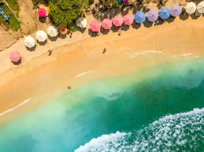 Indonesia. Tropical sandy beach in sunny weather. Turquoise water and beach umbrellas. Aerial view. People on a Tropical Beach. Aerial View