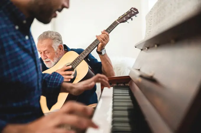 elderly dad and son are playing music at home, relax activity at home with family