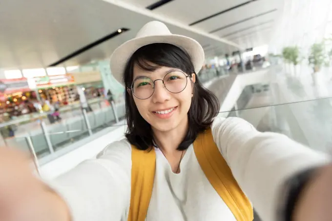 Portrait of young woman traveler wear glasses and hat taking selfie. Happy smiling Girl passenger. Journey, Holiday maker.