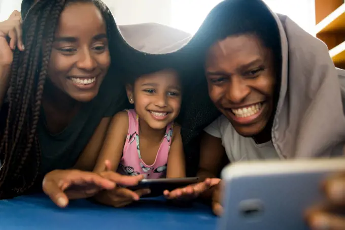 Portrait of a family having fun together and taking a selfie with mobile phone while staying at home.