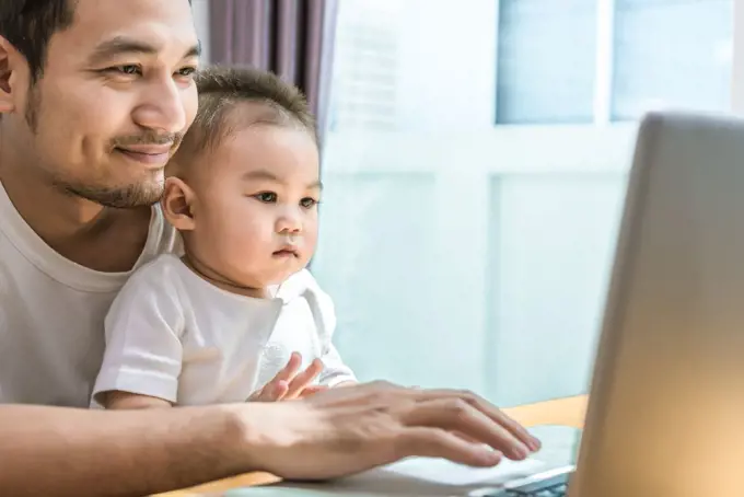 Single dad and son using laptop together happily. Technology and Lifestyles concept. Happy family and baby theme.