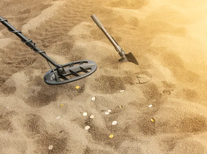 Metal detector, ring and spade on the sand