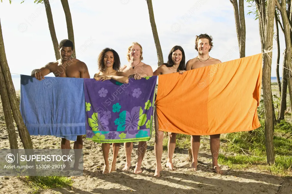 Men and women hiding behind beach towels