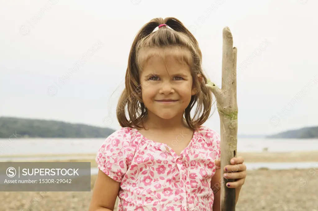 Girl holding driftwood at the beach