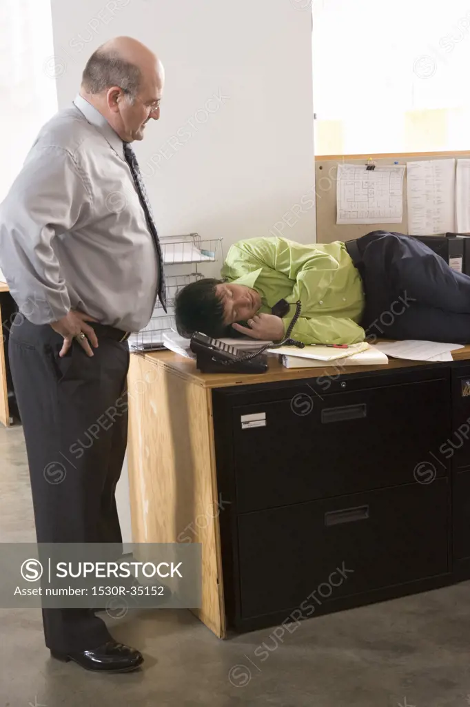 Boss discovering employee asleep on desk