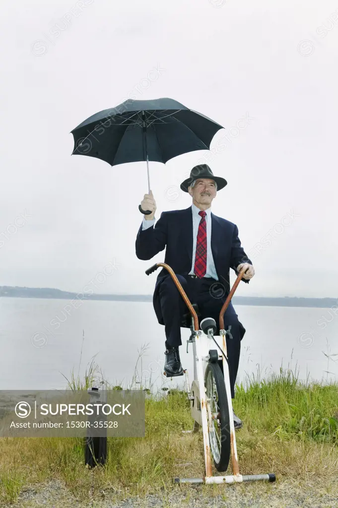 Businessman riding stationary bike near lake