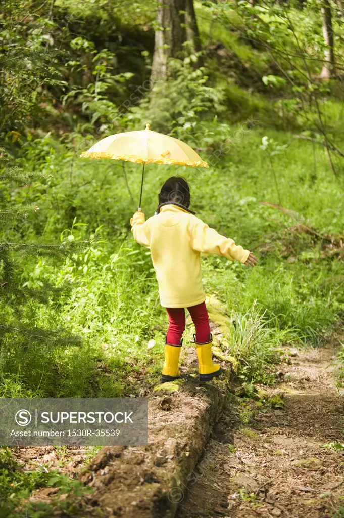 Little girl in woods with umbrella