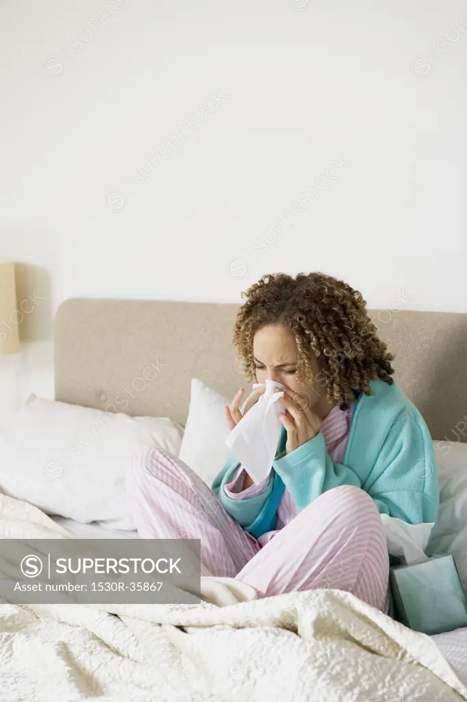 Sick woman in bed blowing nose