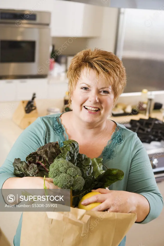 Woman with bag of produce in kitchen