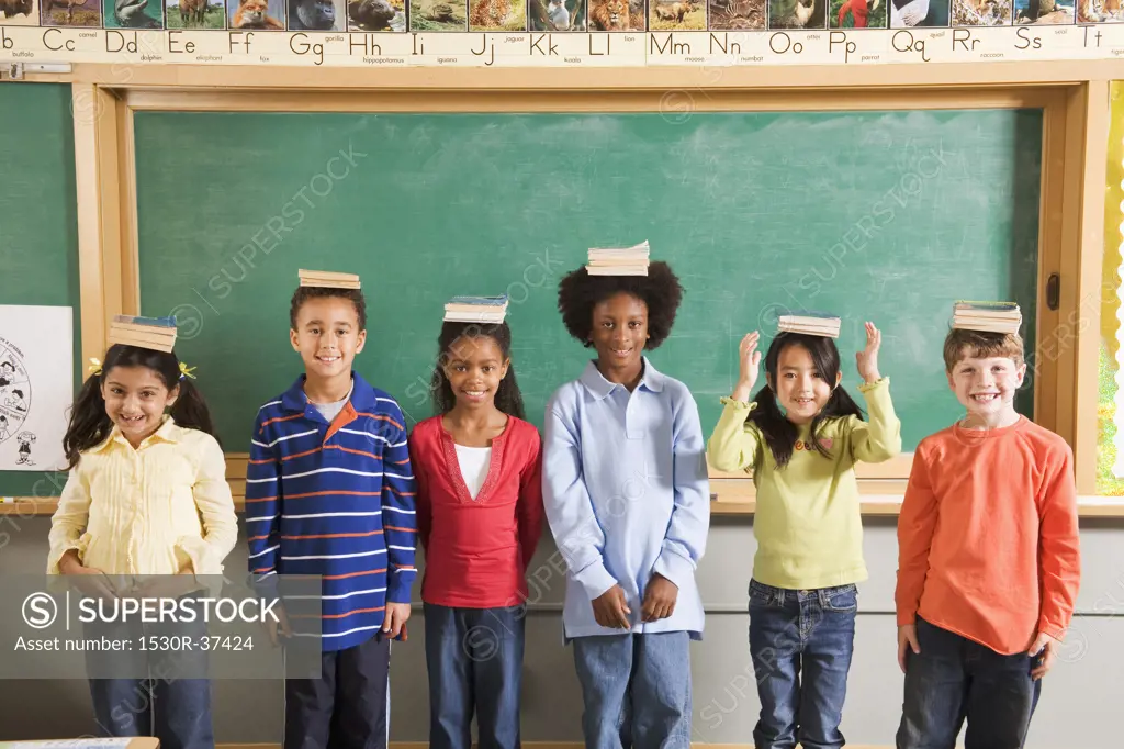 Row of students with books on their heads in classroom