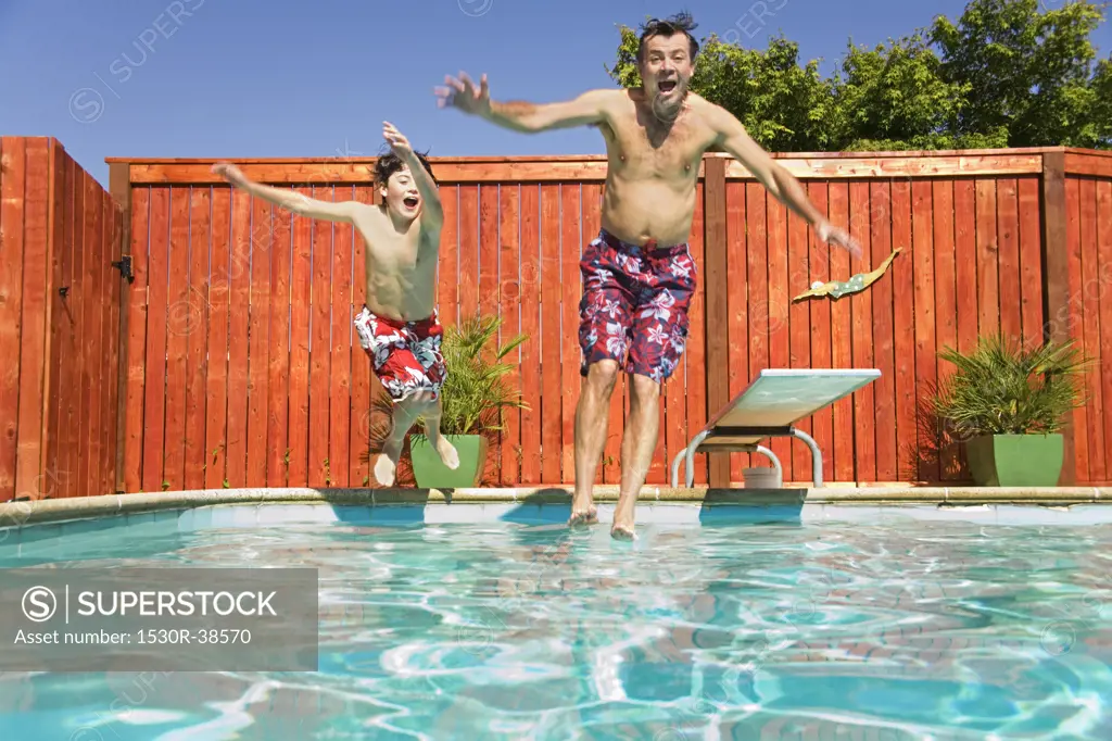 Father and son jumping into swimming pool