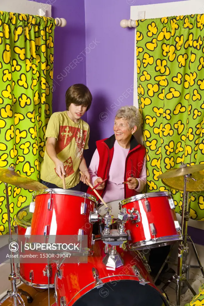Boy showing grandmother how to play drums