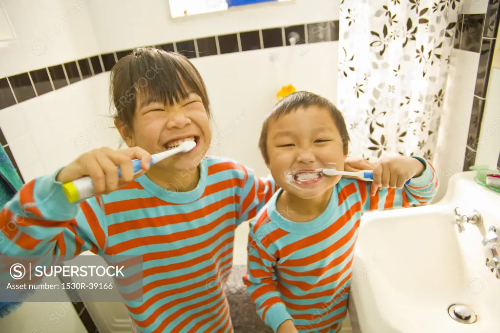 Asian siblings brushing teeth