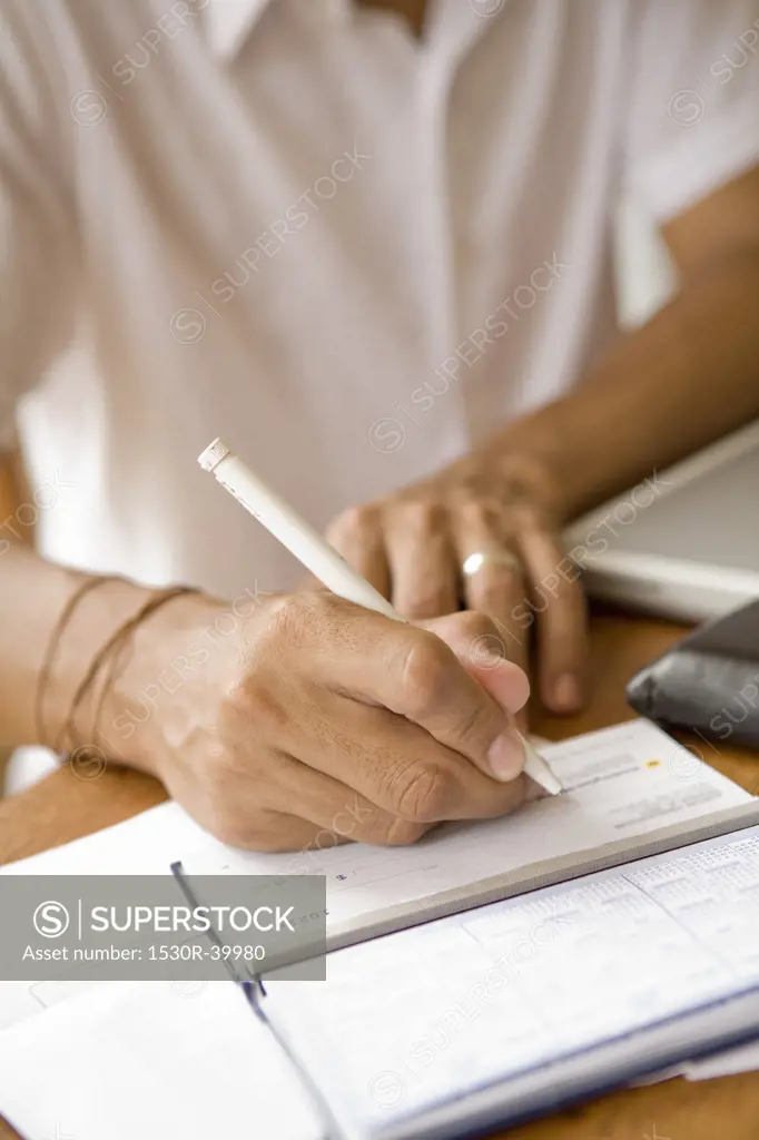 Man signing a check and preparing home finance budget