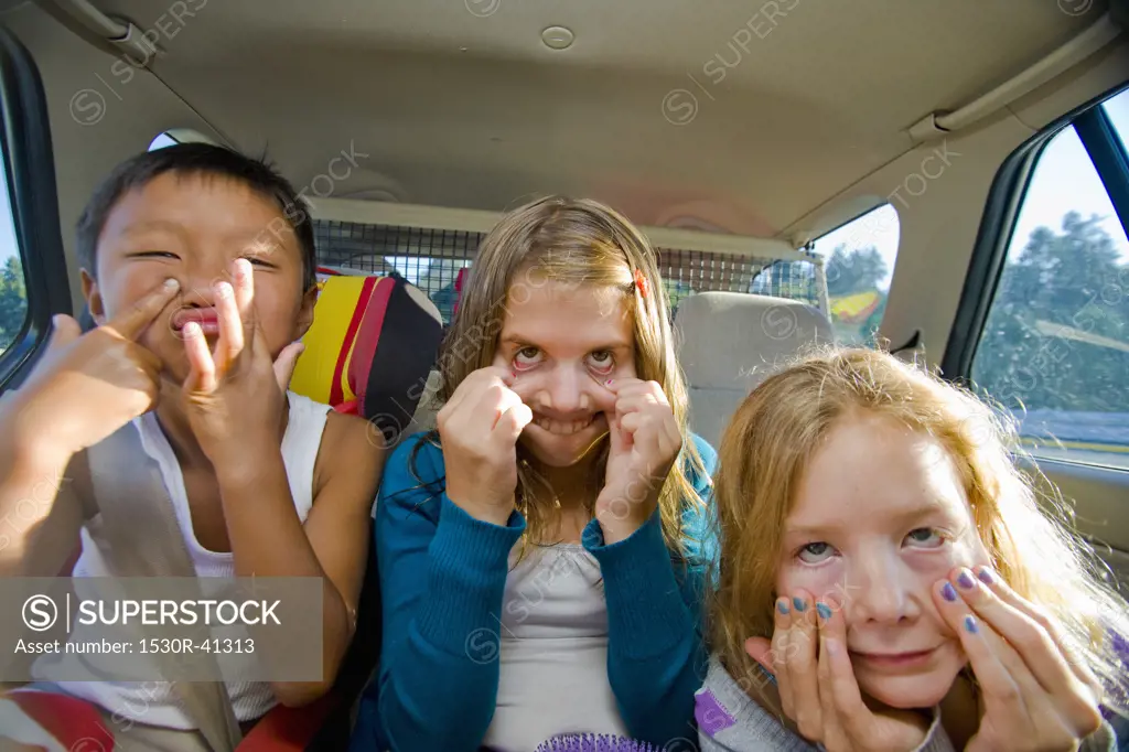 children making faces in car