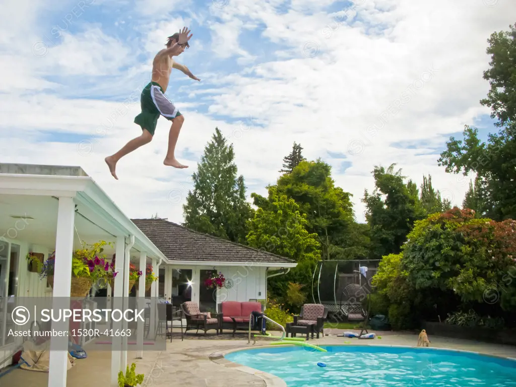 Teen boy jumping off roof into pool