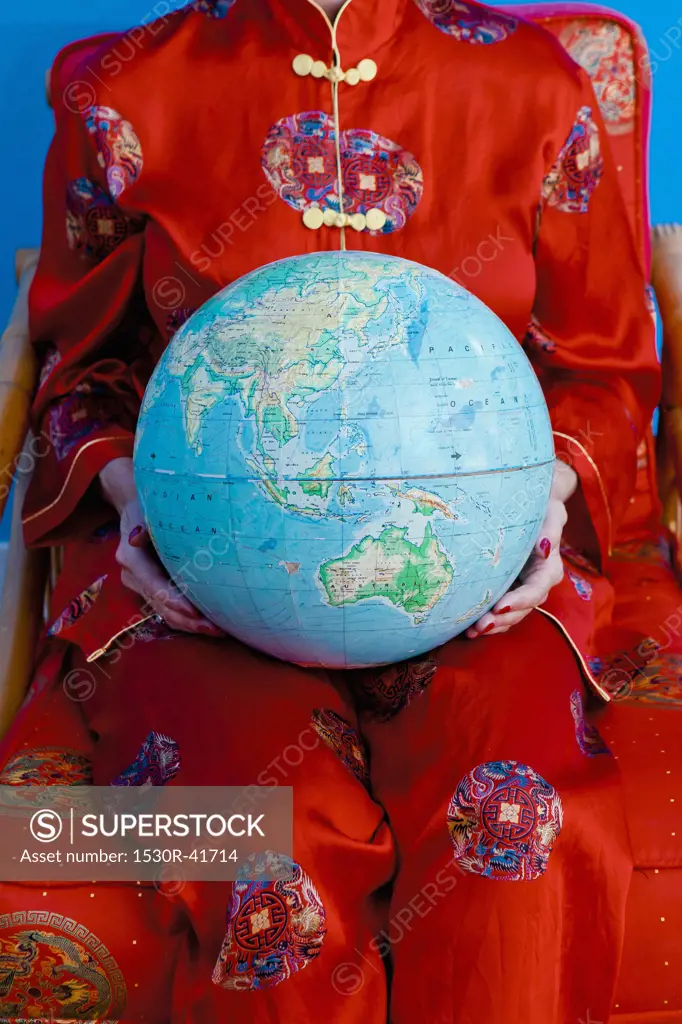 Woman in Chinese pajamas holding globe,
